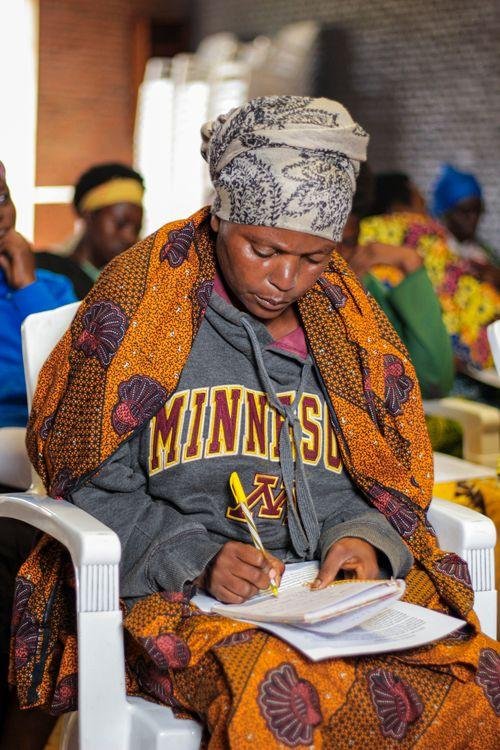 Community workshop participant taking notes in Gitega, Burundi